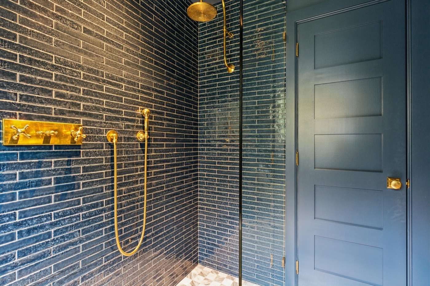 Glynn Gardens primary bath — navy tile shower with brass fixtures